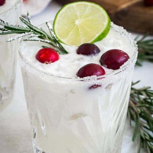 White Christmas margarita topped with fresh cranberries and a lime slice.