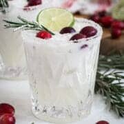 White Christmas margarita with a sugared rim and rosemary and cranberries for garnish.