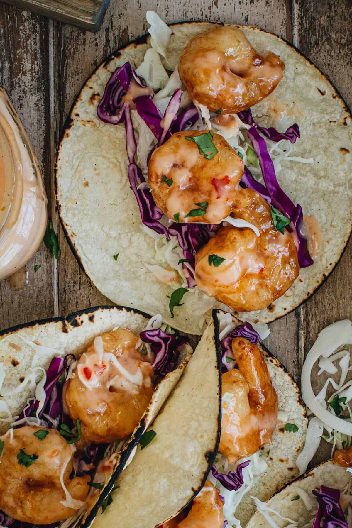 Bang bang shrimp taco with slaw and sauce.