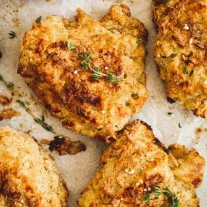 Oven-fried chicken pieces on parchment sprinkled with fresh thyme and coarse salt.