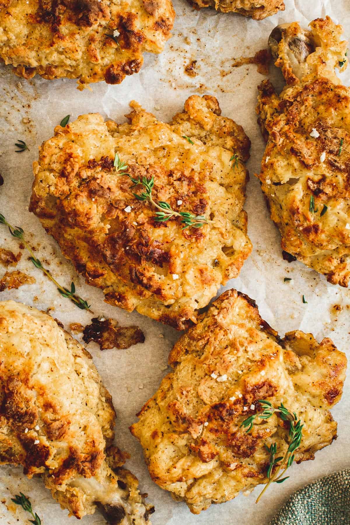 Oven-fried chicken pieces on parchment sprinkled with fresh thyme and coarse salt.