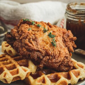 Southern fried chicken and waffles on a white plate.