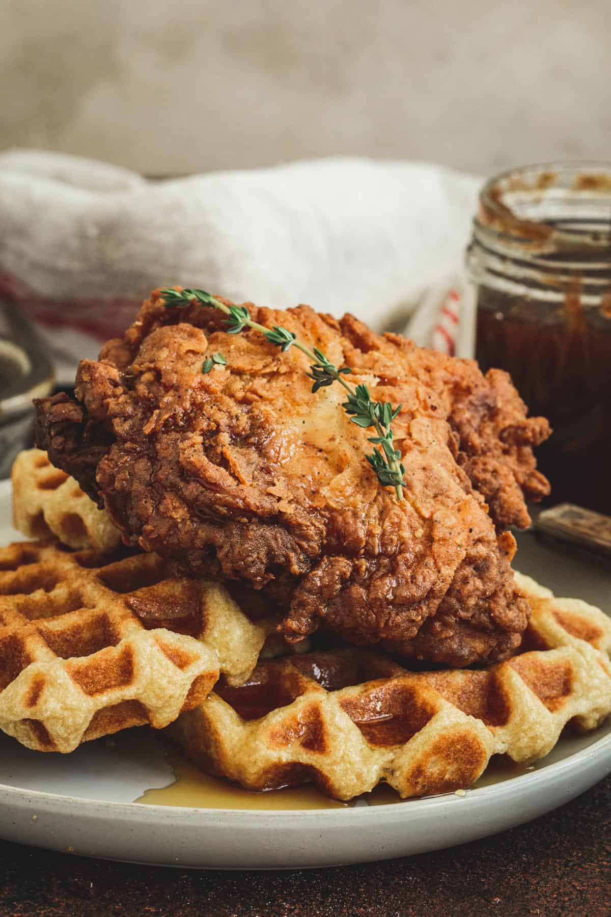 Southern fried chicken and waffles drizzled in syrup on a white plate.