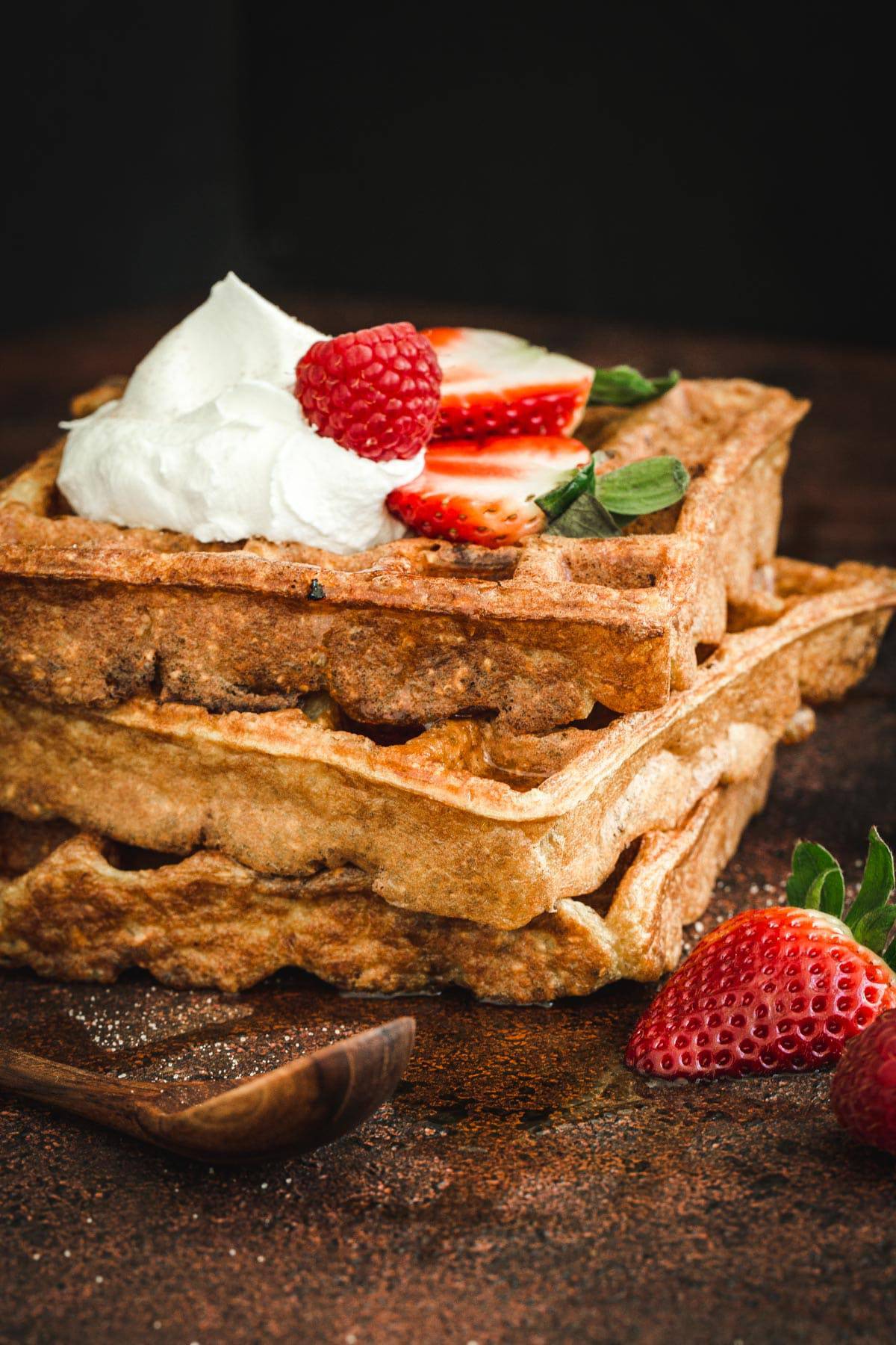 Protein waffles stacked on top of each other with whipped cream and berries.