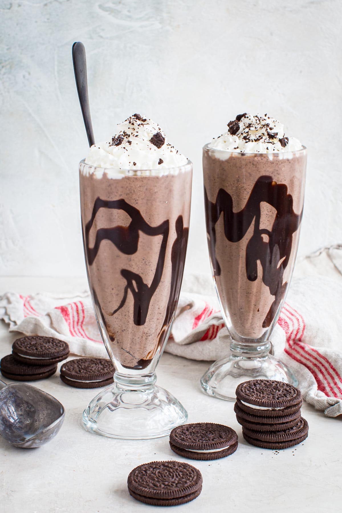 Two Oreo milkshakes topped with whipped cream and crushed Oreos.