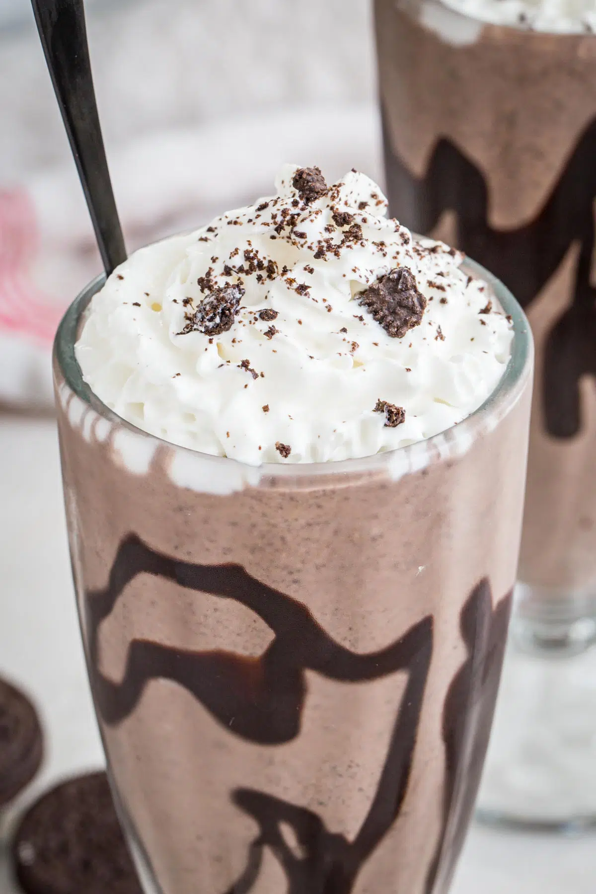 Oreos crumbled on top of whipped topping on top of a milkshake.