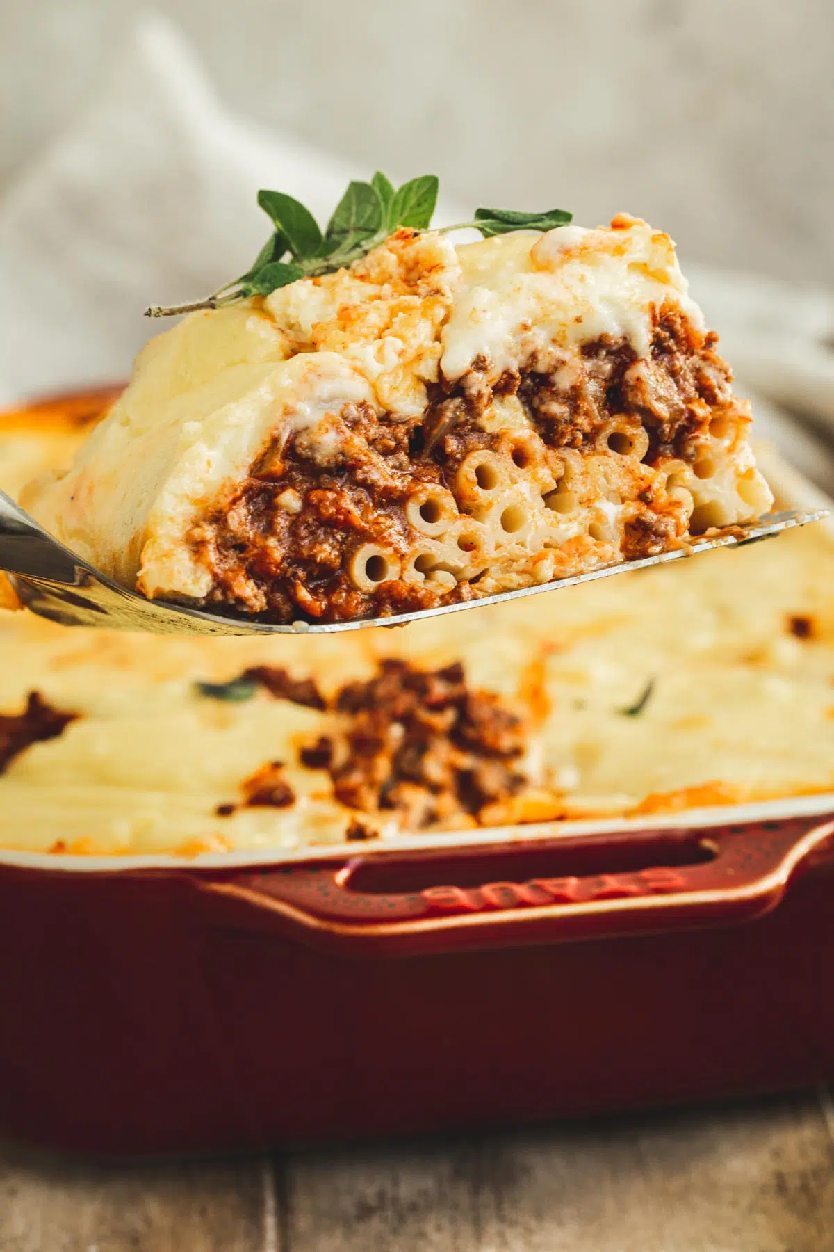 Greek lasagna slice on a spatula.