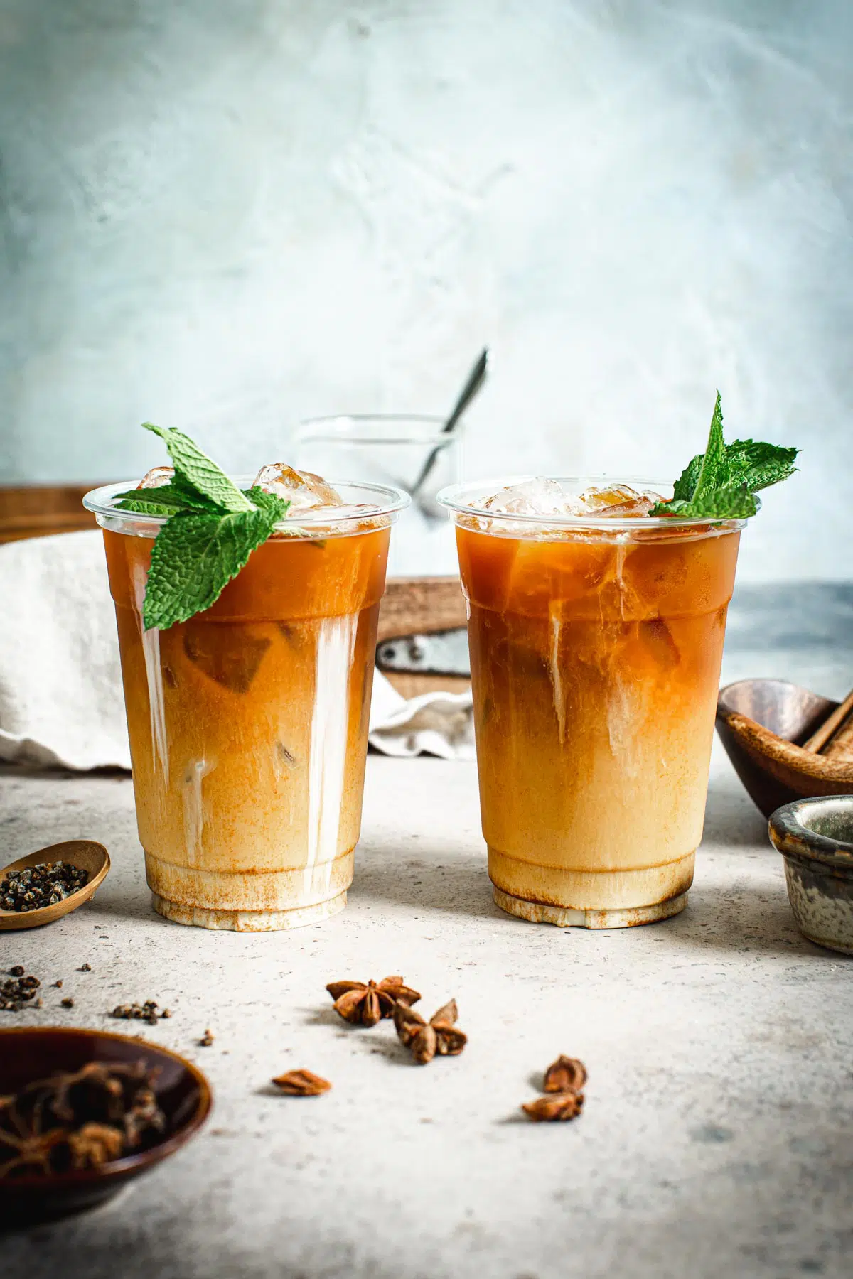 Thai milk tea in plastic cups topped with mint leaves.