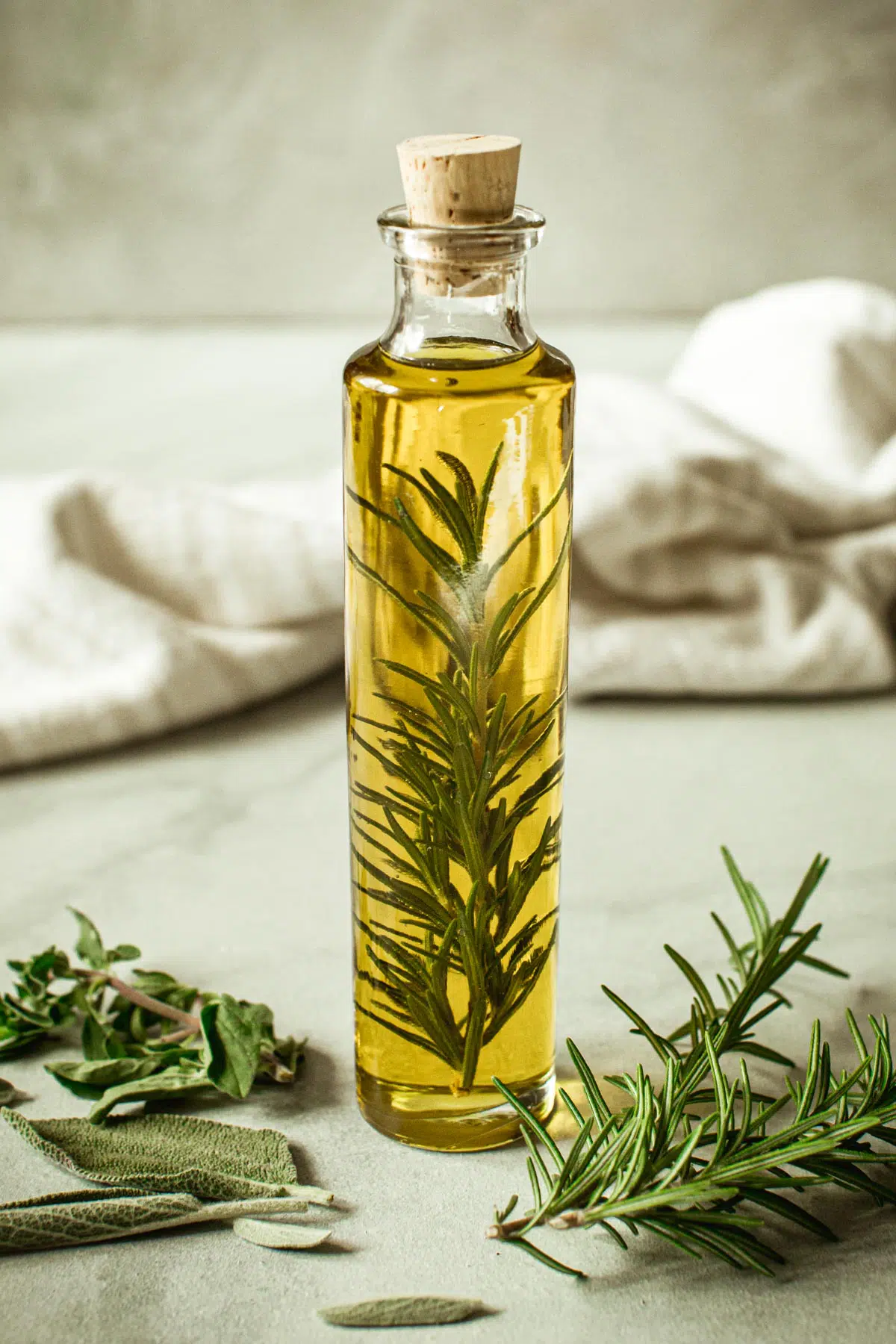 Herb infused olive oil in a bottle with a cork stopper.
