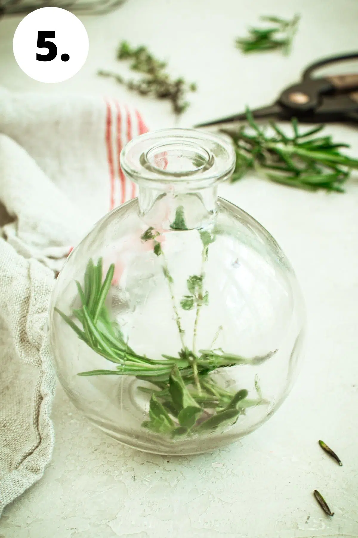 Round glass bottle with herbs inside.