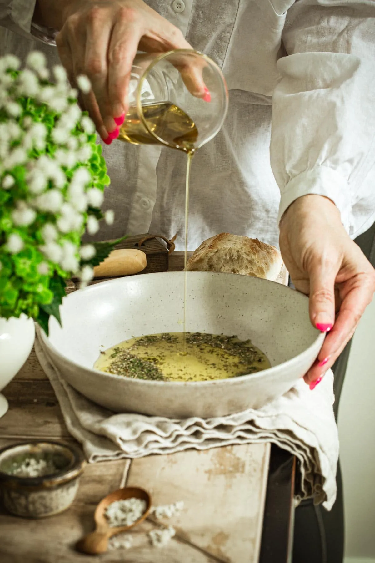 Hand pouring olive oil into a bowl.