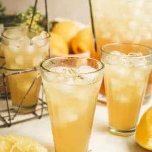 Lavender lemonade in a glass with a pitcher behind it.