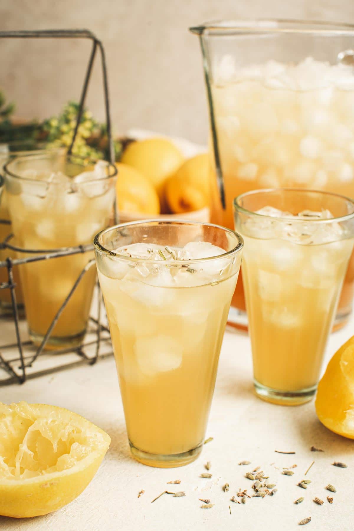 Lavender lemonade in a glass with a pitcher and additional glasses with lemonade behind it.