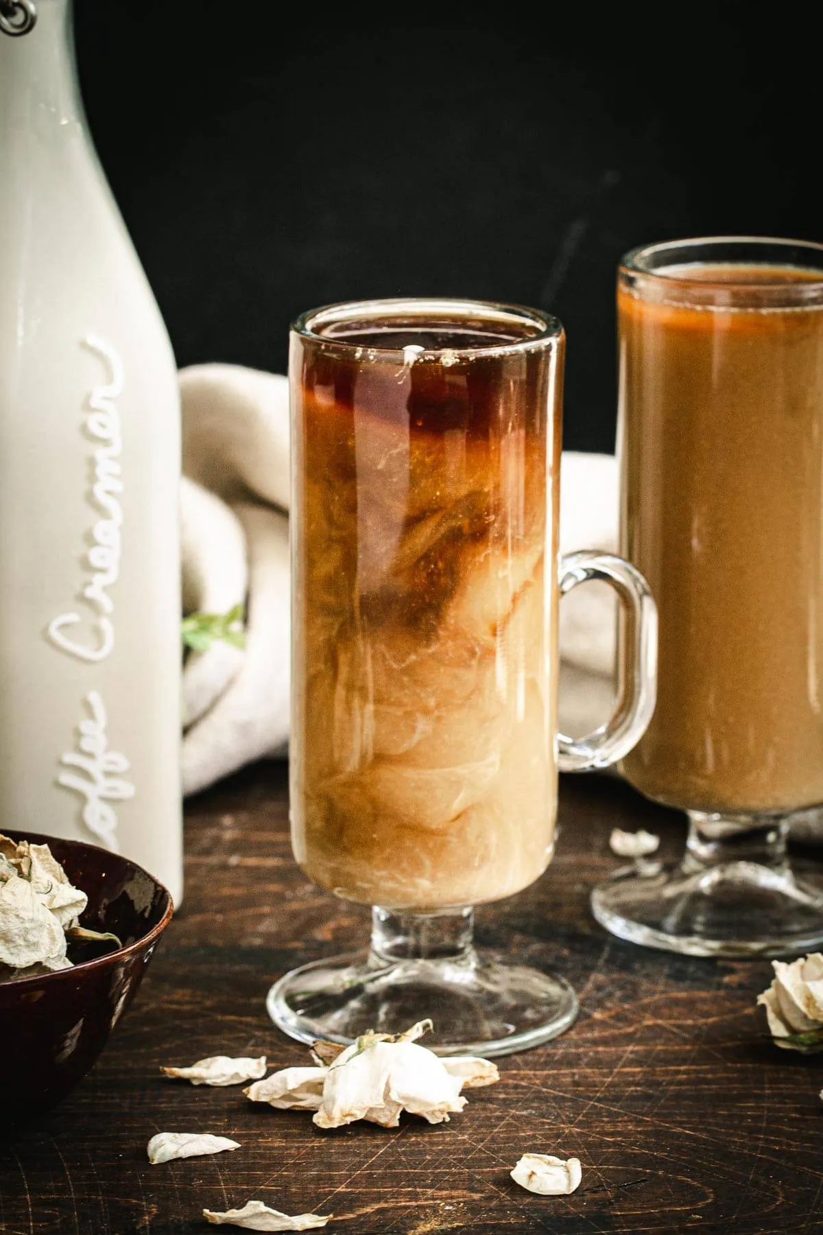 Vegan homemade coffee creamer and coffee in a tall and thin coffee mug with creamer sitting next to it.