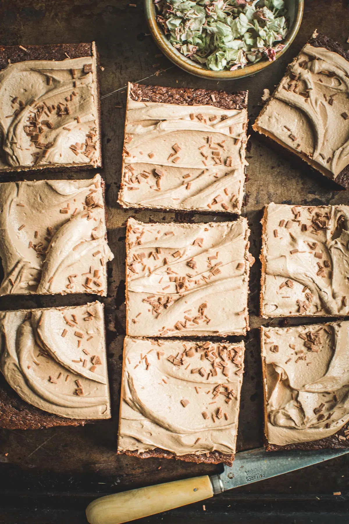 Brownie cake cut into squares with milk chocolate frosting.