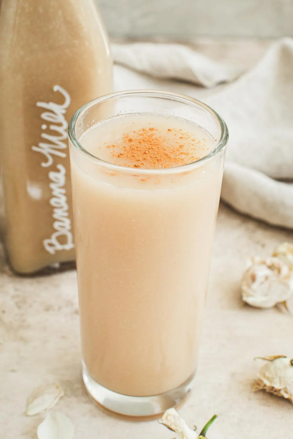 Banana milk in a glass topped with cinnamon.