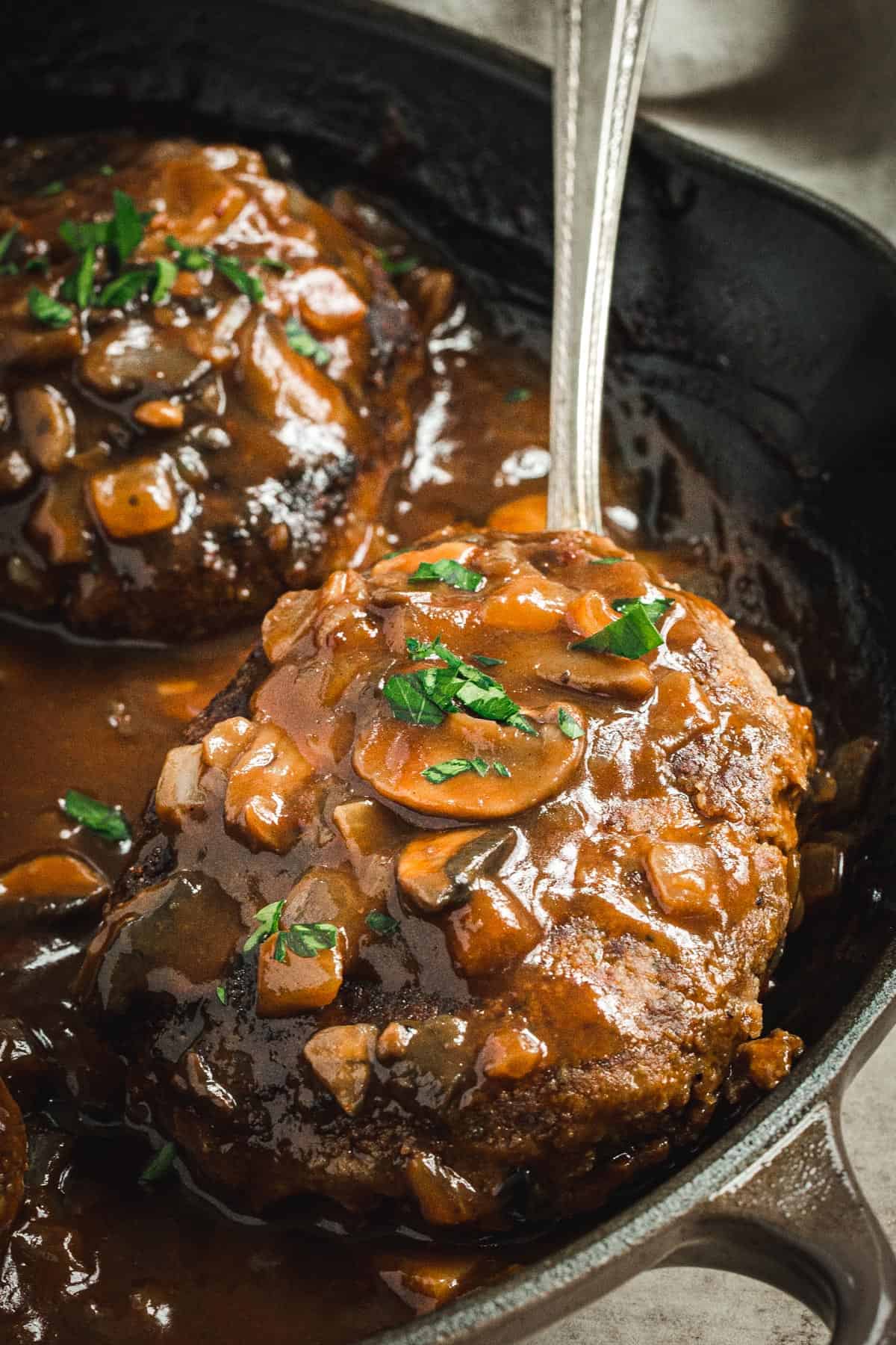 Salisbury steak with mushroom gravy in a skillet.