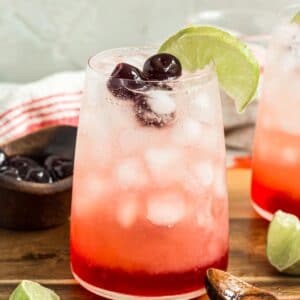Shirley temple drink with cherries and a lime wedge.