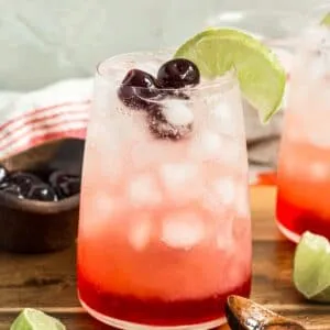 Shirley temple drink with cherries and a lime wedge.