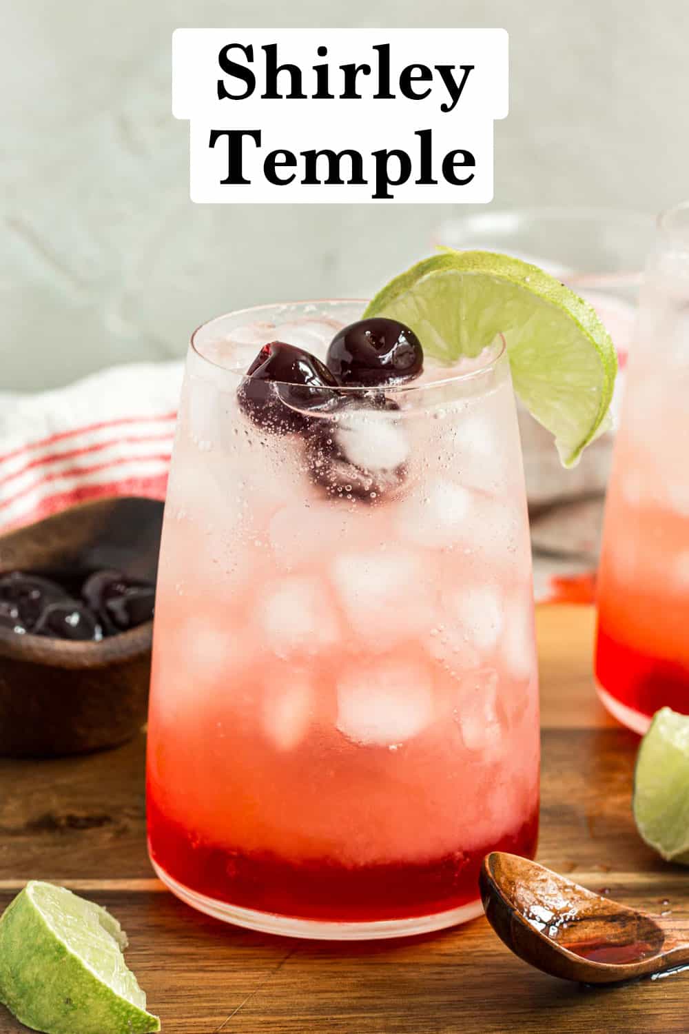 Shirley Temple drink topped with Maraschino cherries and a lime wedge.