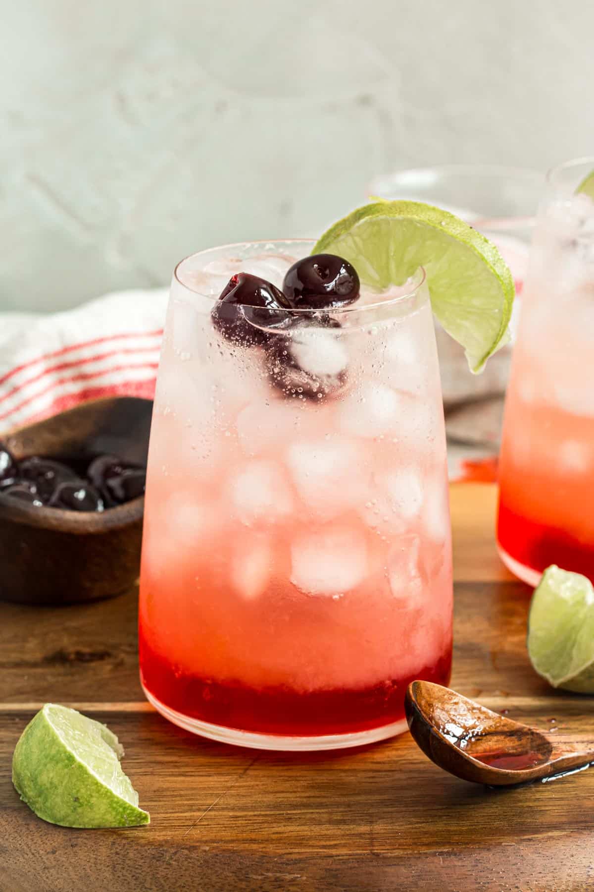 Shirley temple drink with cherries and a lime wedge.