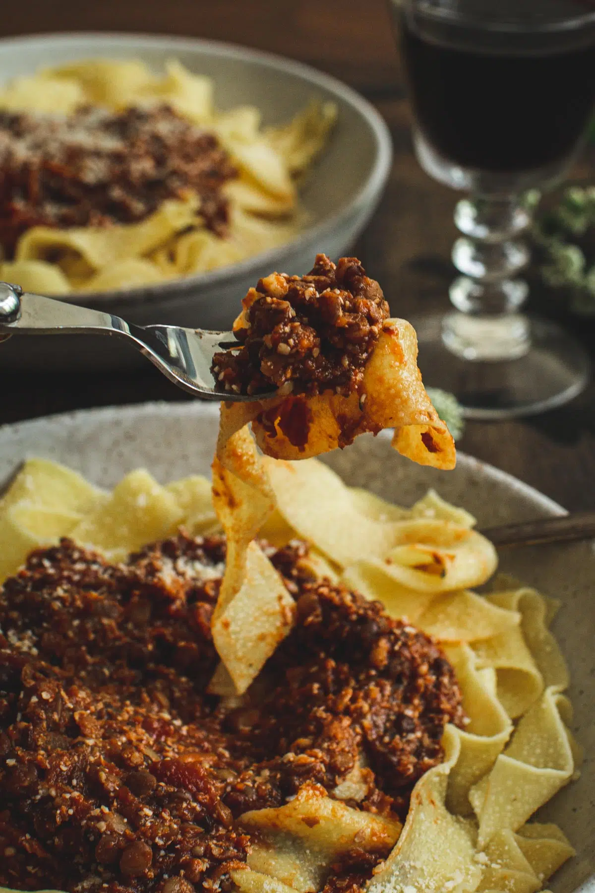 Lentil bolognese and pappardelle noodles on a fork.