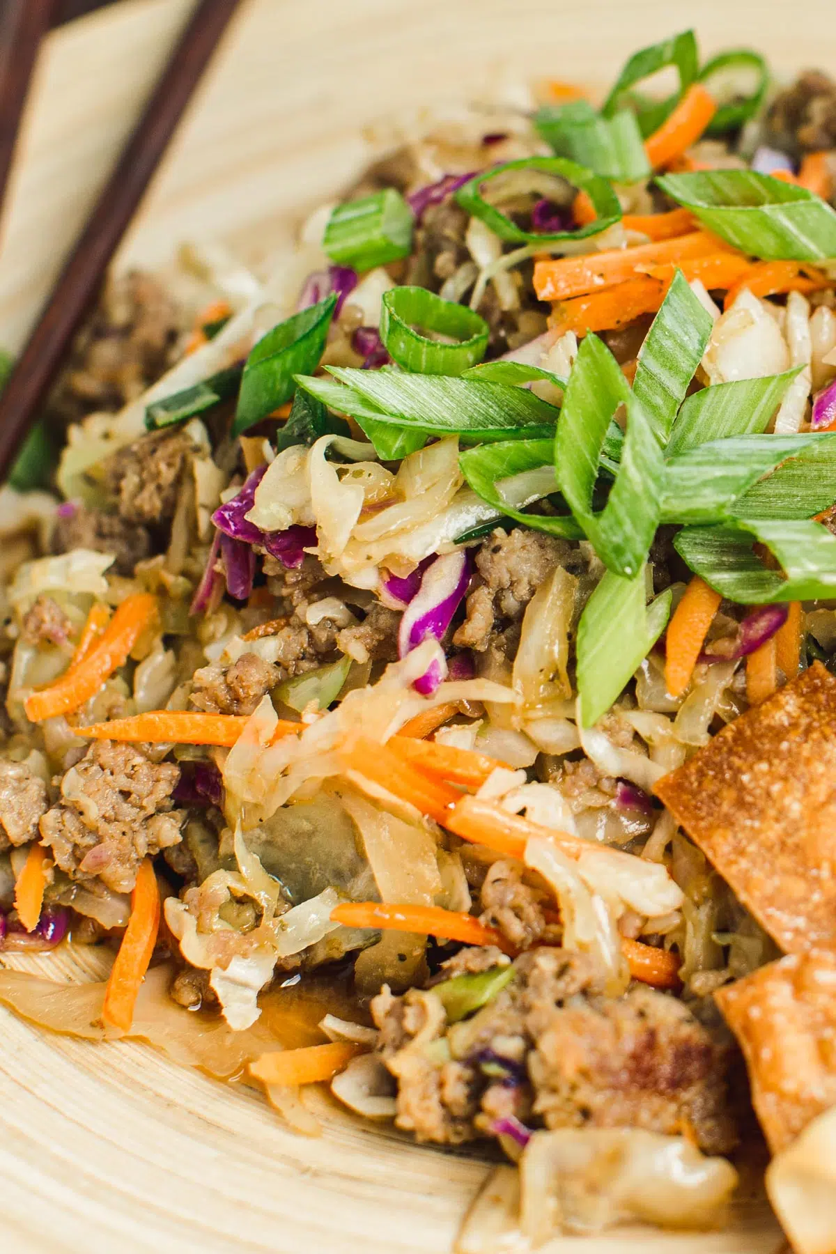 Egg roll in a bowl topped with chopped green onions.