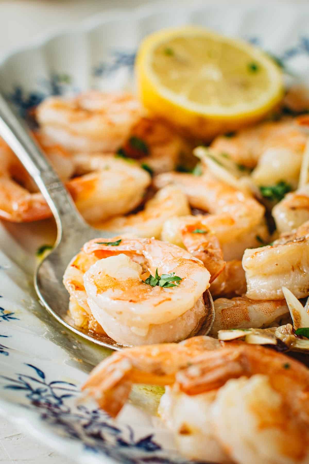 Garlic shrimp scampi on a platter with a silver serving spoon.