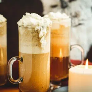 Harry Potter butterbeer in a tall glass with whipped cream spilling over the side.