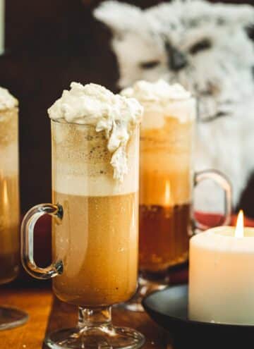 Harry Potter butterbeer in a tall glass with whipped cream spilling over the side.