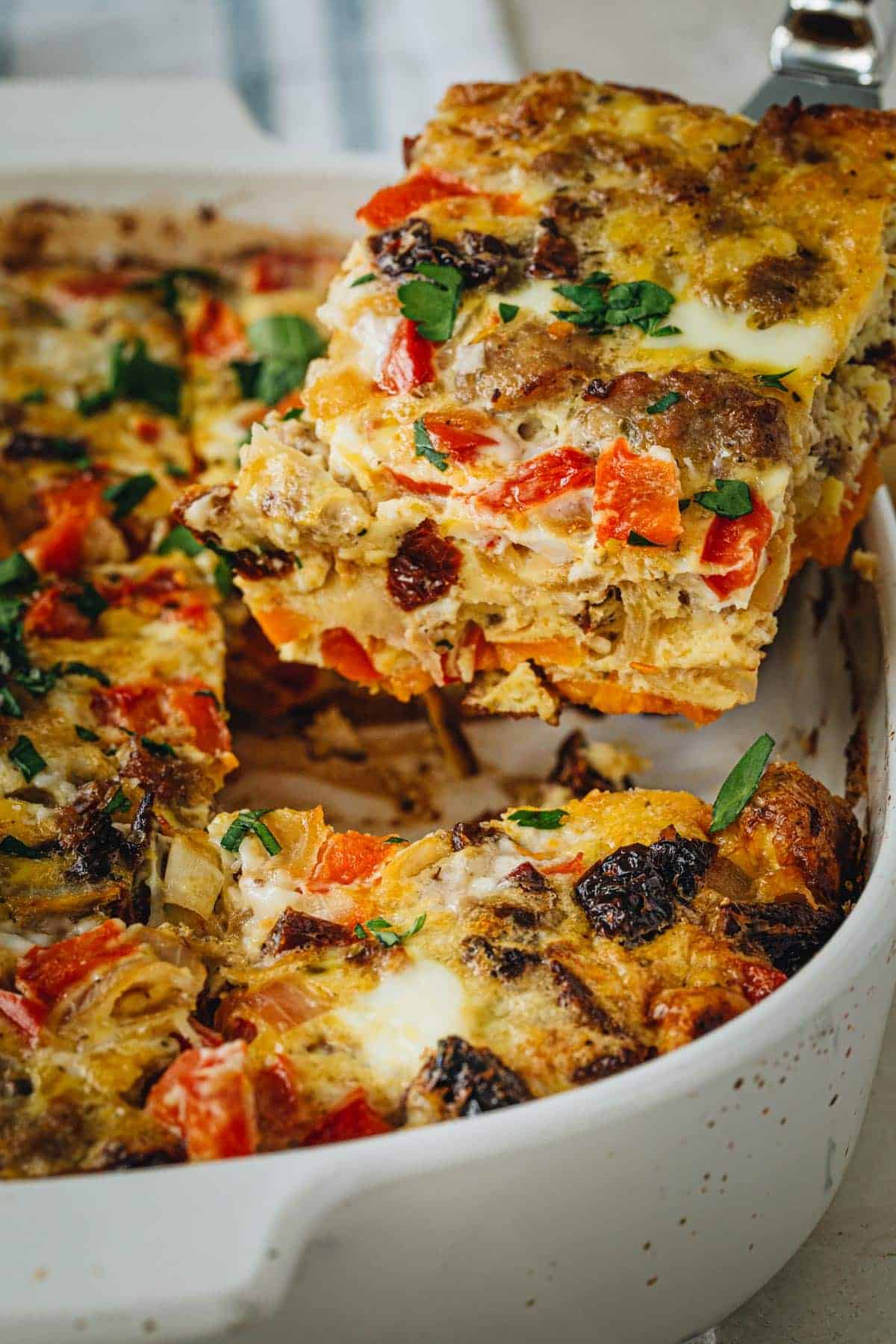 Sausage and egg casserole slice being lifted from casserole dish.