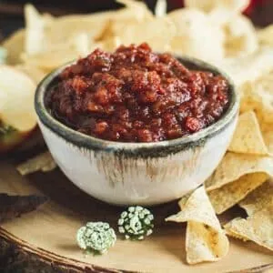 Tomato apple salsa in a bowl with chips around it.