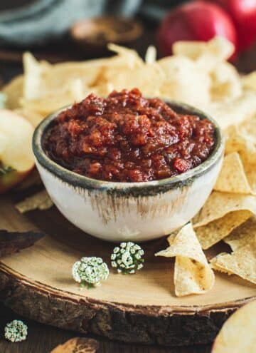 Tomato apple salsa in a bowl with chips around it.