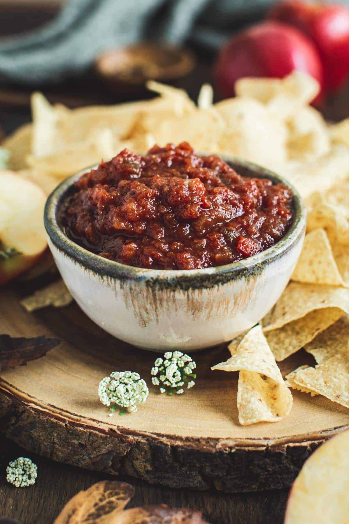 Tomato apple salsa in a bowl with chips around it.