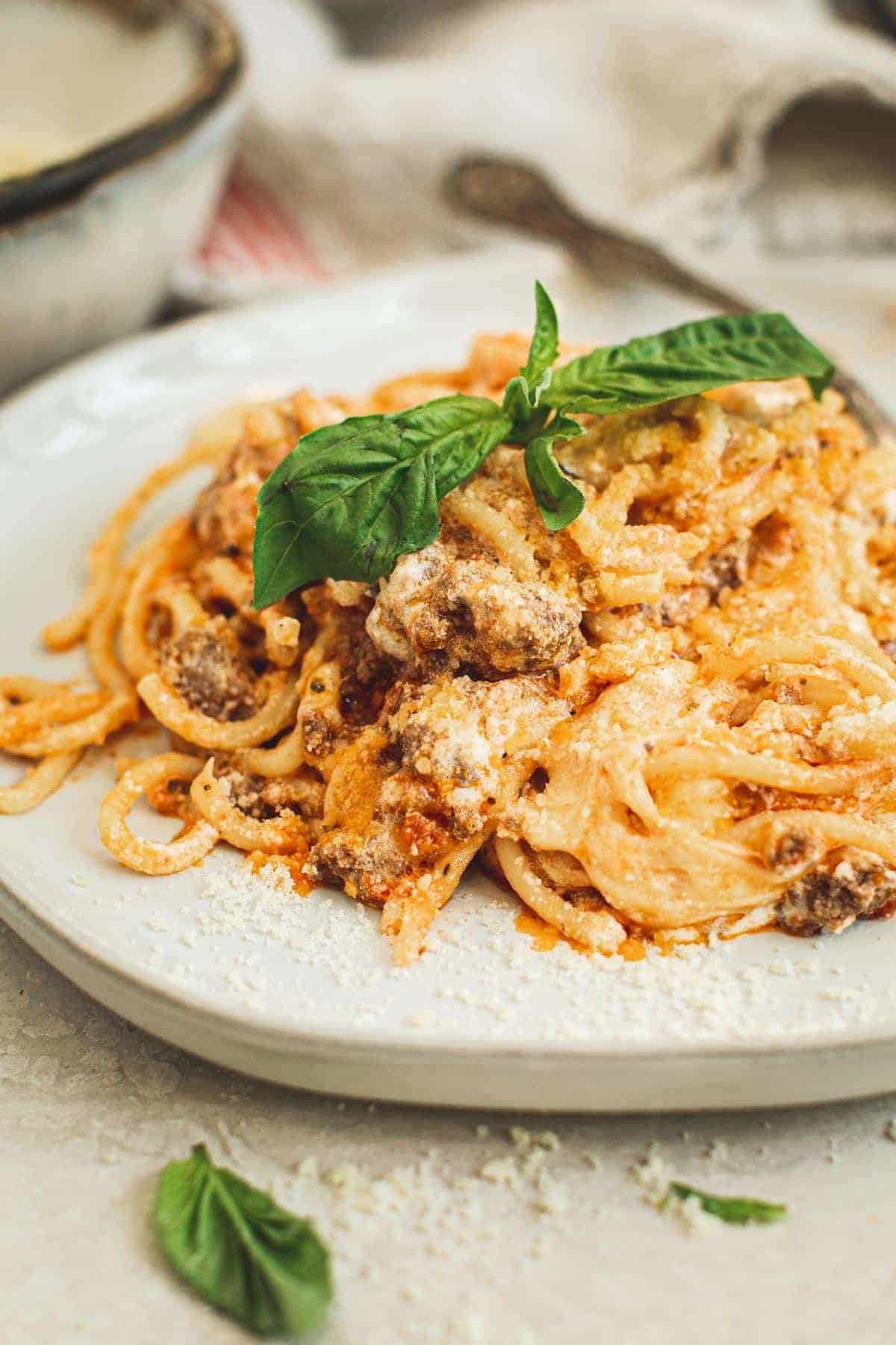 Easy baked spaghetti on a plate topped with fresh basil.