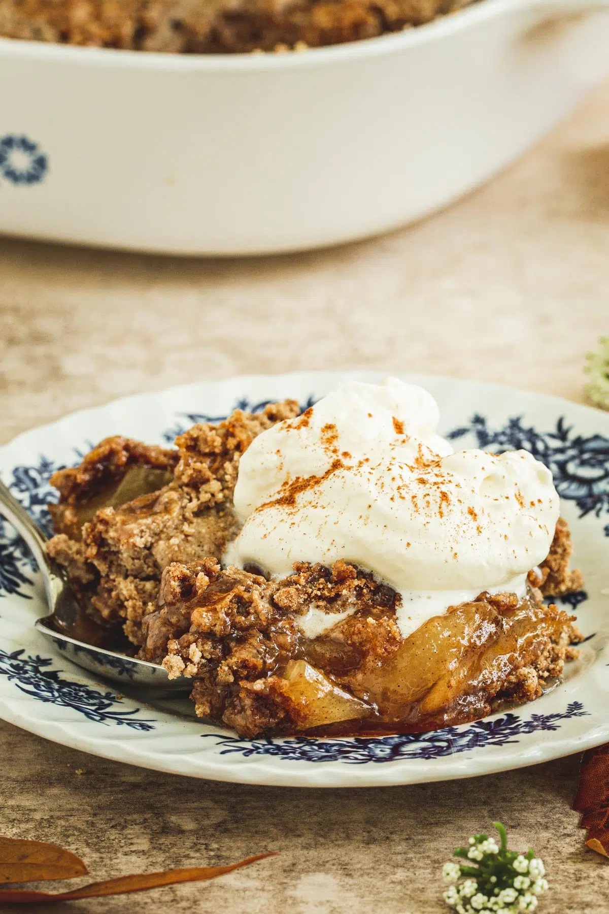 Easy caramel apple dump cake topped with whipped cream on a dessert plate.