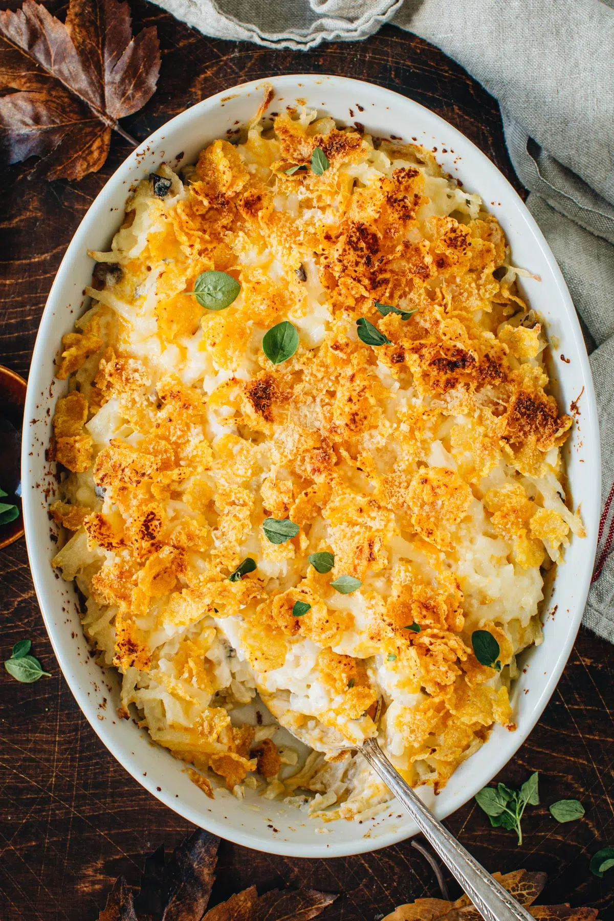 Cheesy hashbrown casserole with a silver serving spoon.