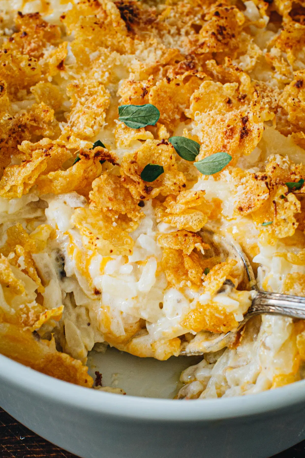 Close up of cheesy hashbrown casserole with a silver serving spoon.