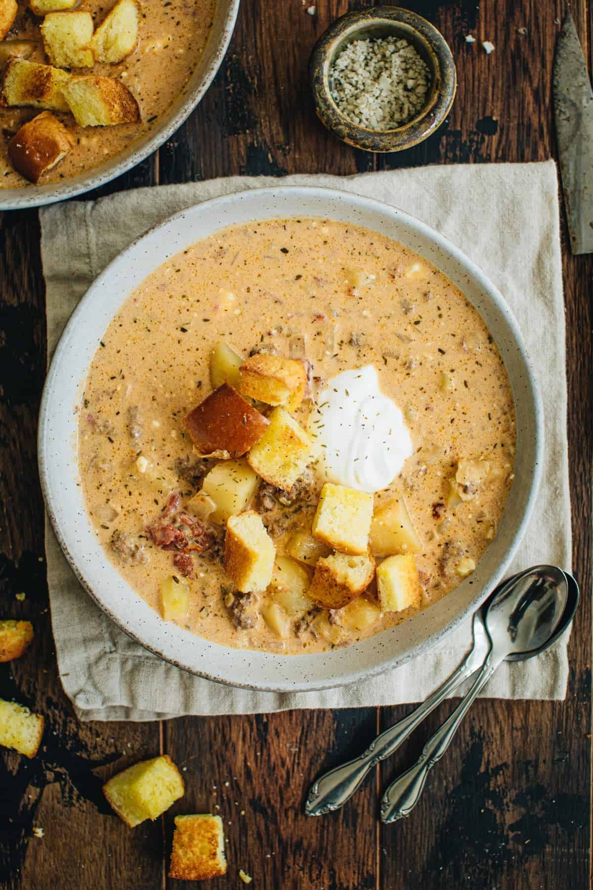 Crockpot cheeseburger soup topped with hamburger bun croutons and sour cream.