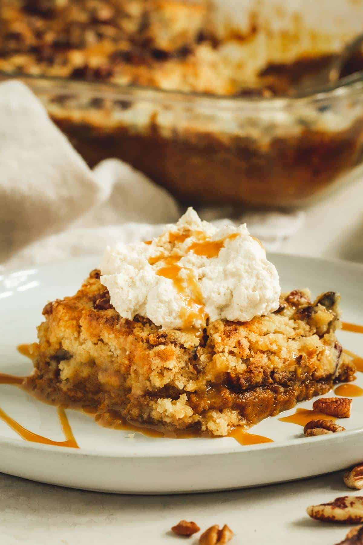 Easy pumpkin dump cake topped with whipped cream on a white plate.