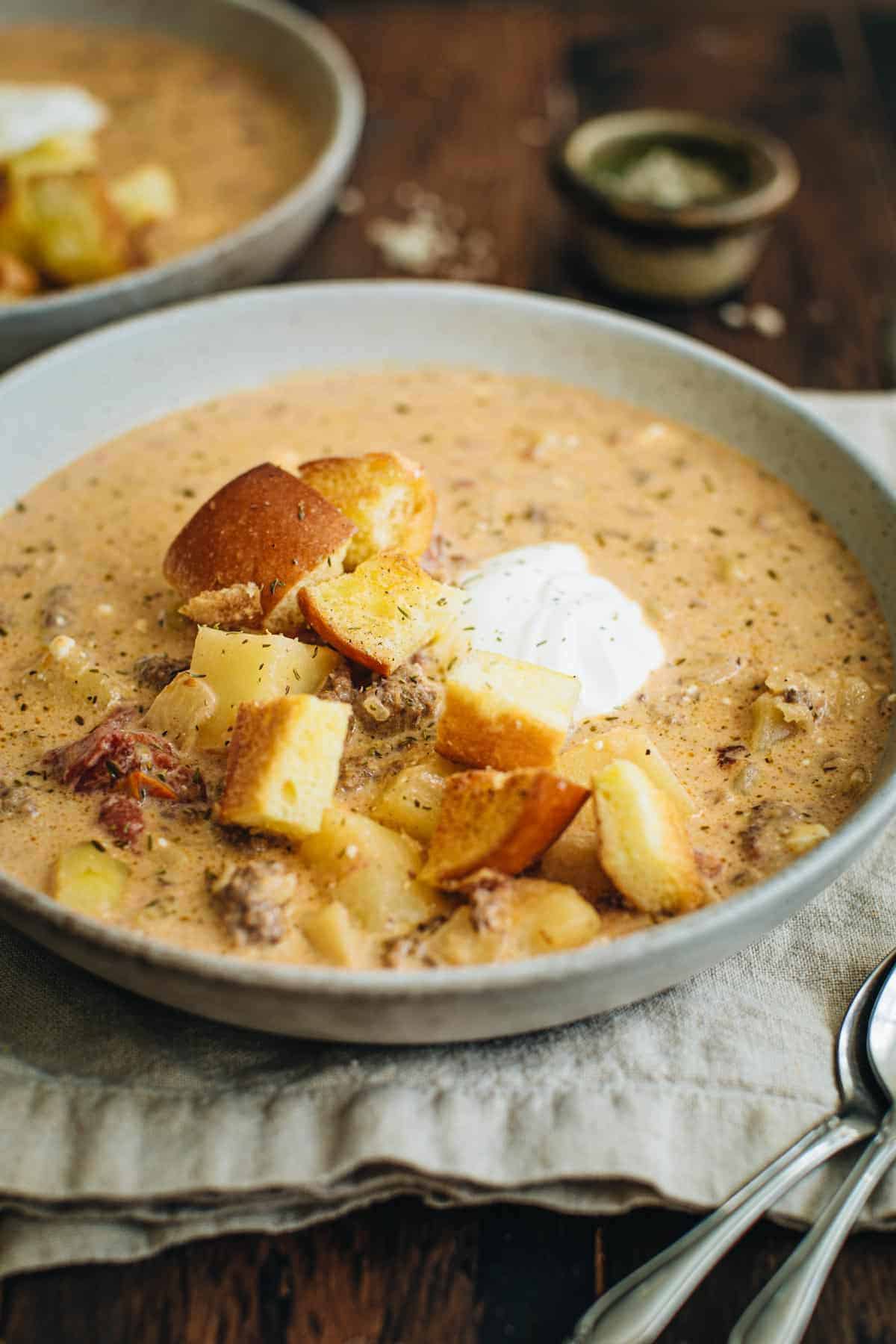 Hamburger soup in the slow cooker topped with hamburger bun croutons.