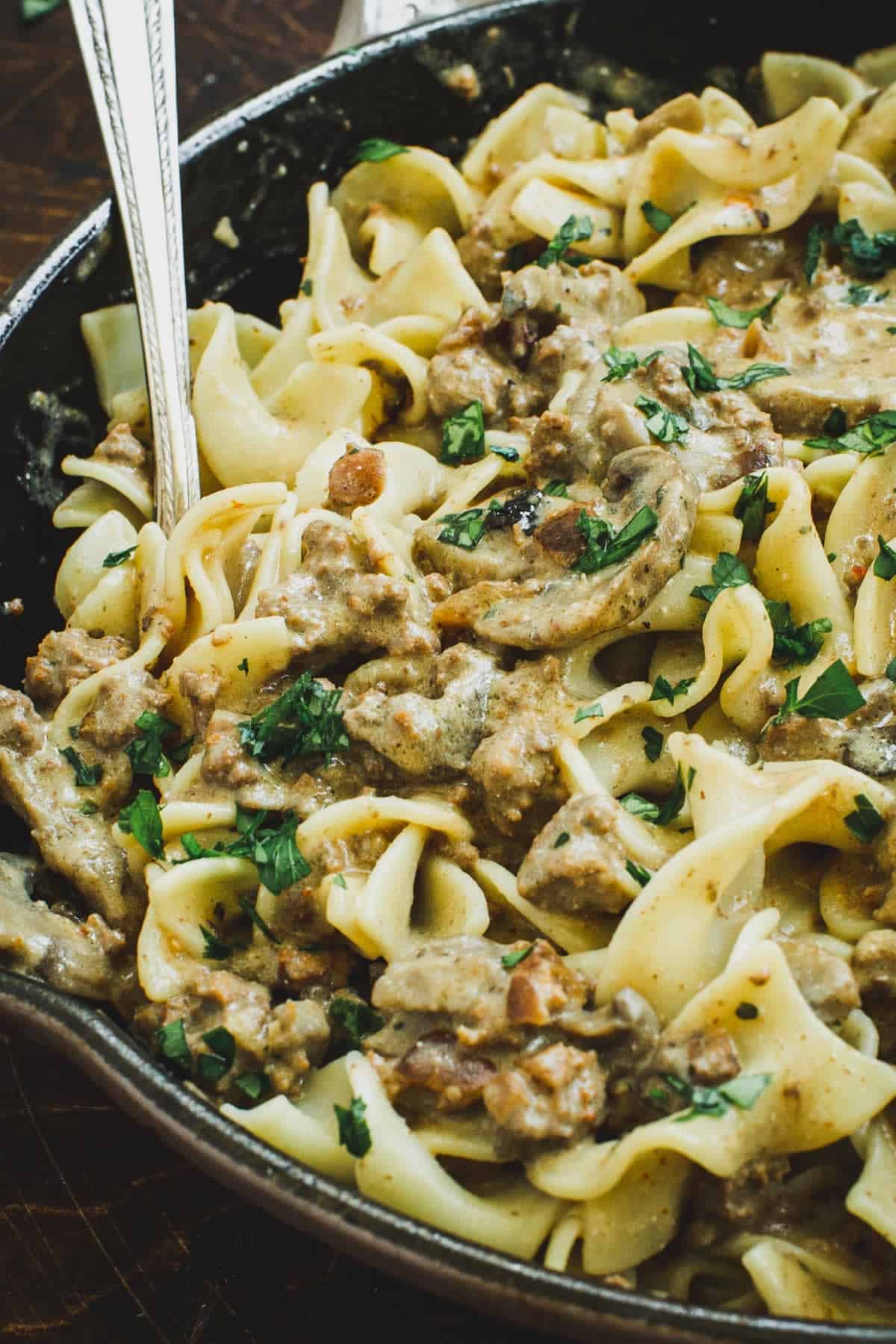 Hamburger stroganoff in a skillet with a serving spoon.