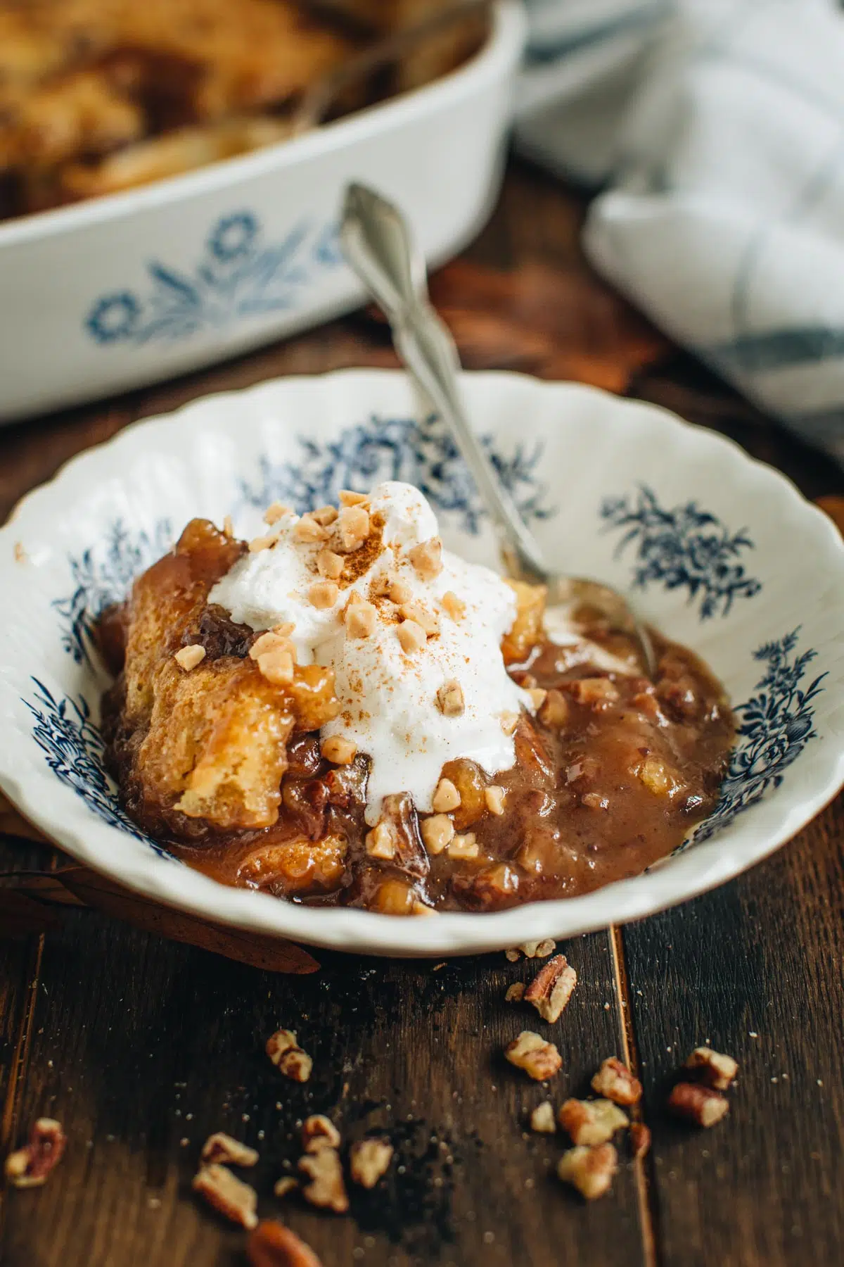 Easy pecan pie cobbler in a blue and white dessert bowl topped with whipped cream.