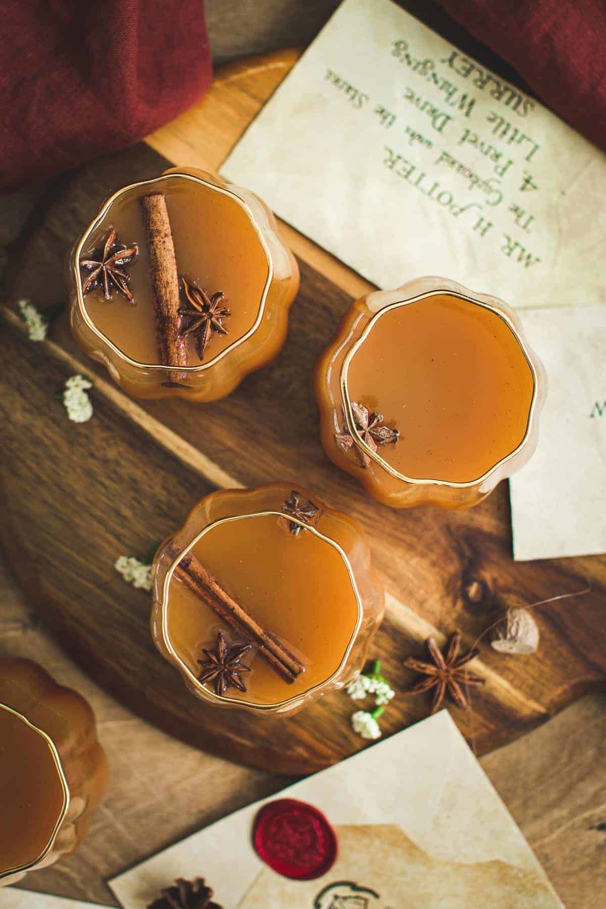 Harry Potter pumpkin juice in glasses sitting on a wooden cutting board.