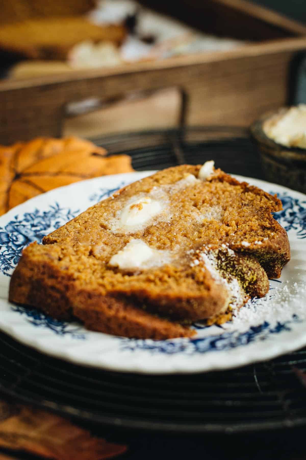 Slice of pumpkin banana bread with butter on top.