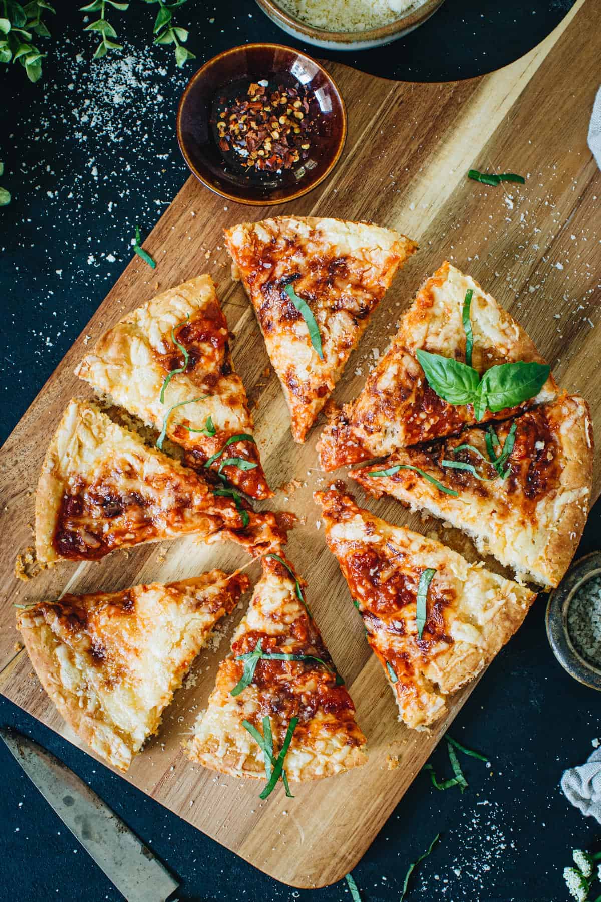 Cast iron skillet pizza sliced on a wooden cutting board.