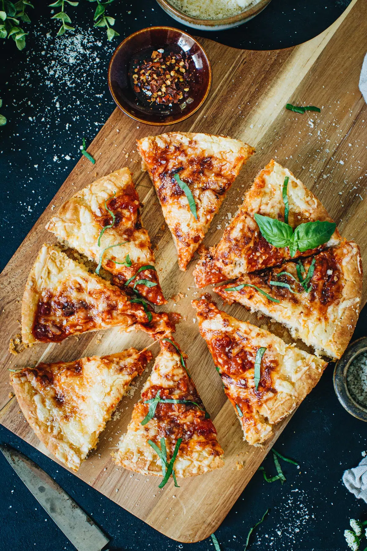 Cast iron skillet pizza sliced on a wooden cutting board.