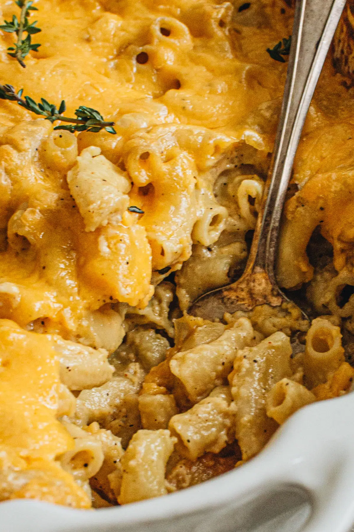 Southern baked mac and cheese in a white baking dish with a silver serving spoon.