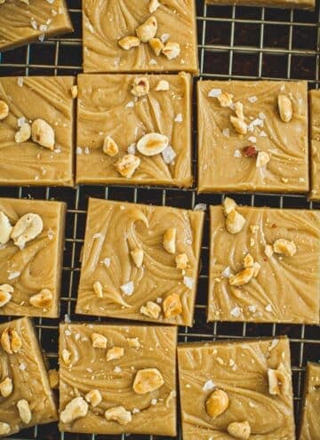Squares of homemade peanut butter fudge topped with sea salt and chopped peanuts.