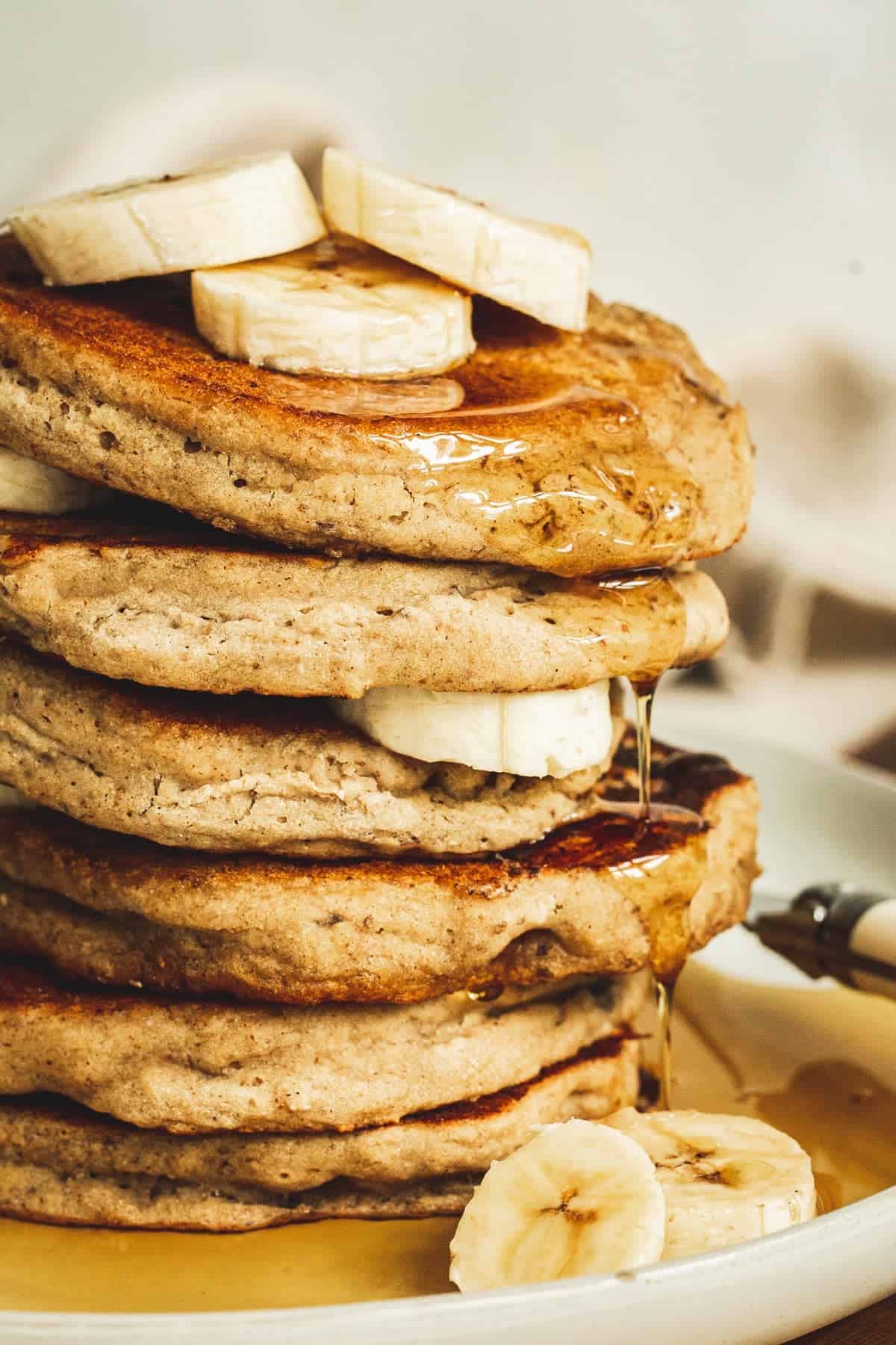 Vegan banana pancakes with banana slices stacked.